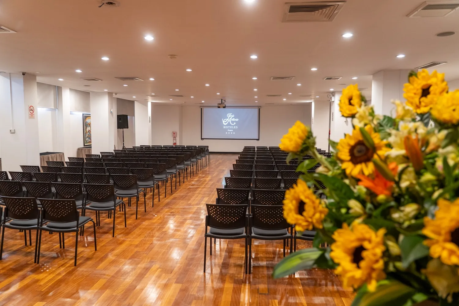 Salón de eventos del Hotel José Antonio Deluxe montado en filas frente a la pantalla