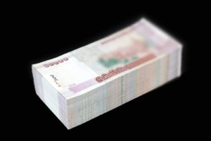 Pila de billetes de banco de 50.000 unidades sobre fondo negro, mostrando el anverso y los cantos de los billetes.