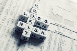 Letras de Scrabble formando la palabra 'PROFITS' sobre páginas de un periódico financiero con tablas de índices bursátiles y un gráfico de líneas.