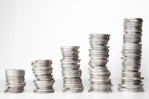 Cinco pilas de monedas de diferentes alturas sobre un fondo blanco