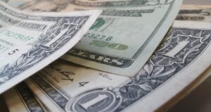 Primer plano de varios billetes de un dólar estadounidense superpuestos y parcialmente doblados.