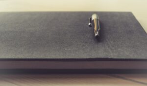 Bolígrafo metálico sobre un cuaderno cerrado para llevar un registro de operaciones